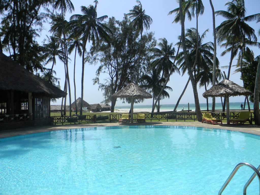 Poollandschaft im Hotel in Kenia mit Palmen und Blick auf das Meer